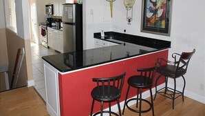 Une cuisine dotée d’un îlot central, de tabourets de bar et d’un réfrigérateur.