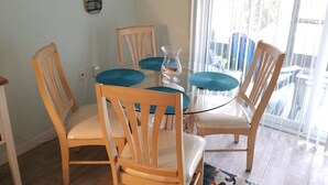 Un comedor con una mesa redonda de cristal, sillas de madera y un jarrón pequeño.