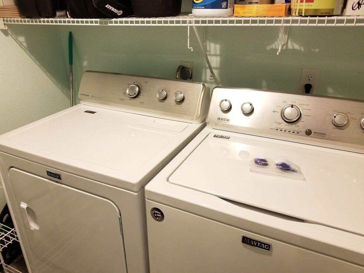 Un área de lavandería con dos lavadoras y secadoras blancas Maytag.