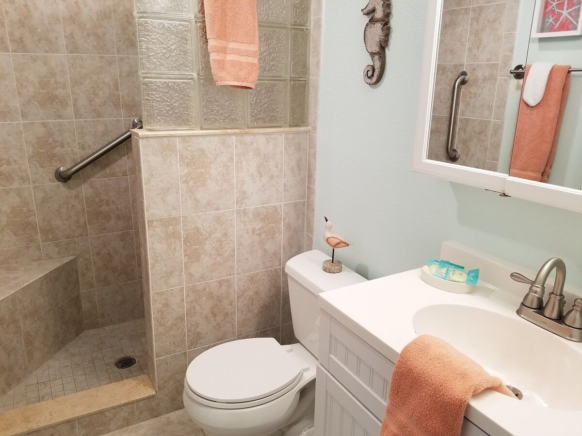 A bathroom with a shower, toilet, sink, and a decorative bird statue.