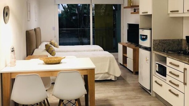 Habitación de hotel compacta con zona de comedor, cama y kitchenette.