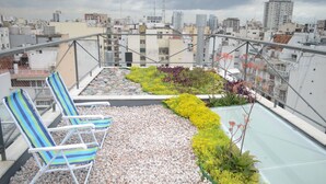 Terraza en la azotea con jardín, zona de estar y vistas al horizonte de la ciudad.