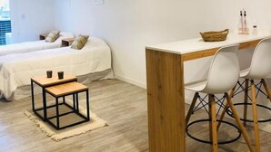 Un dormitorio moderno con cama, mesitas de noche, un escritorio y sillas.