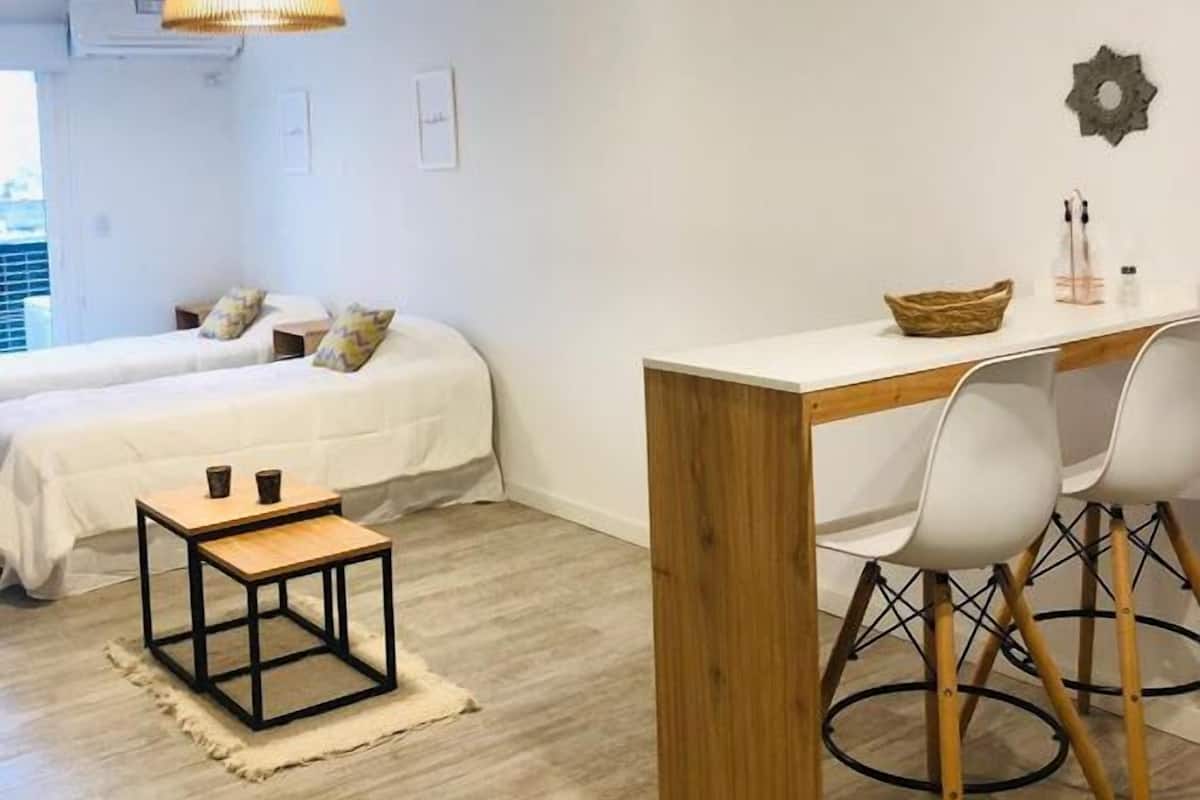A modern bedroom with a bed, bedside tables, a desk, and chairs.