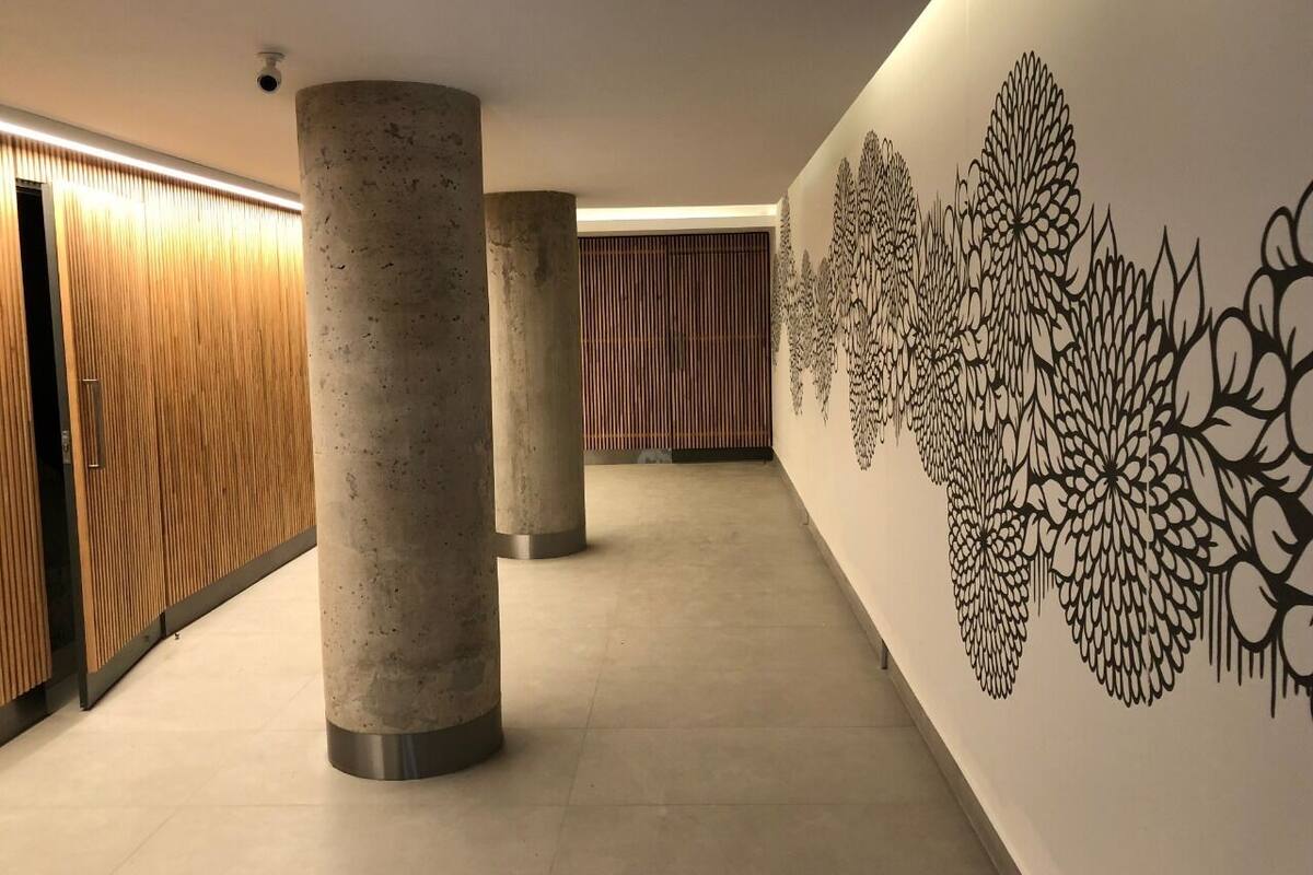 A corridor with concrete pillars, wooden paneling, and a decorative wall with floral patterns.