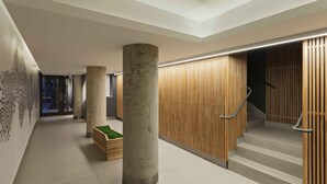 Un interior moderno con una columna central de hormigón, pared de listones de madera y una escalera.