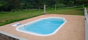 A rectangular swimming pool with a white edge, surrounded by a concrete deck.