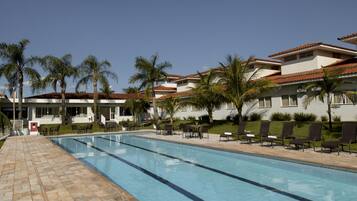 Una piscina al aire libre, sombrillas, tumbonas