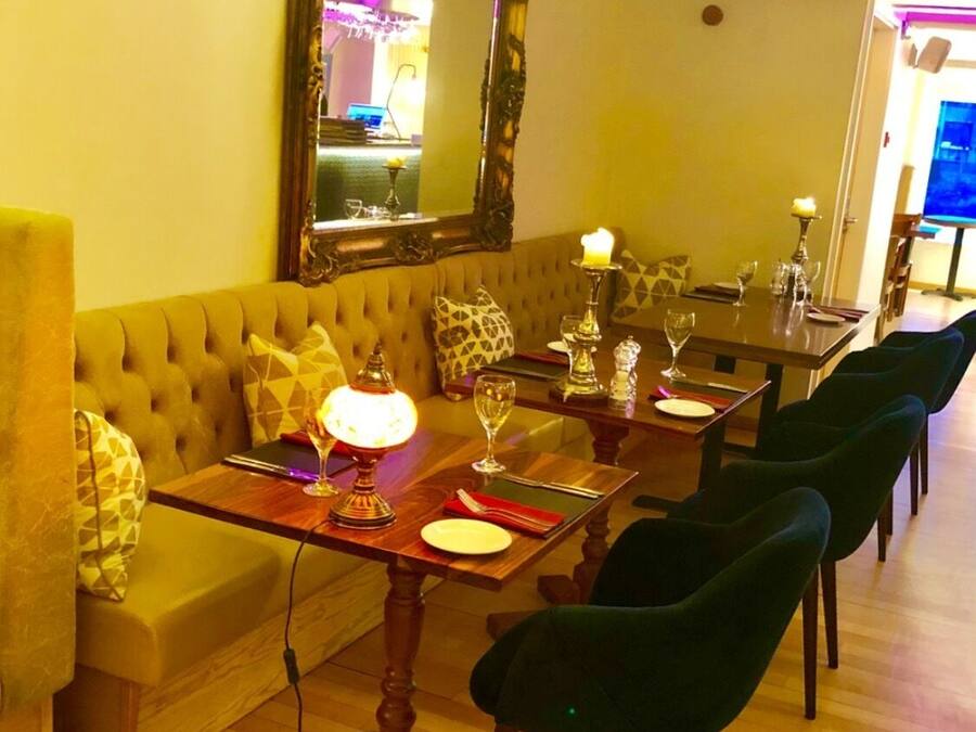Un comedor con una mesa lista para cuatro personas, un sofá y un espejo.