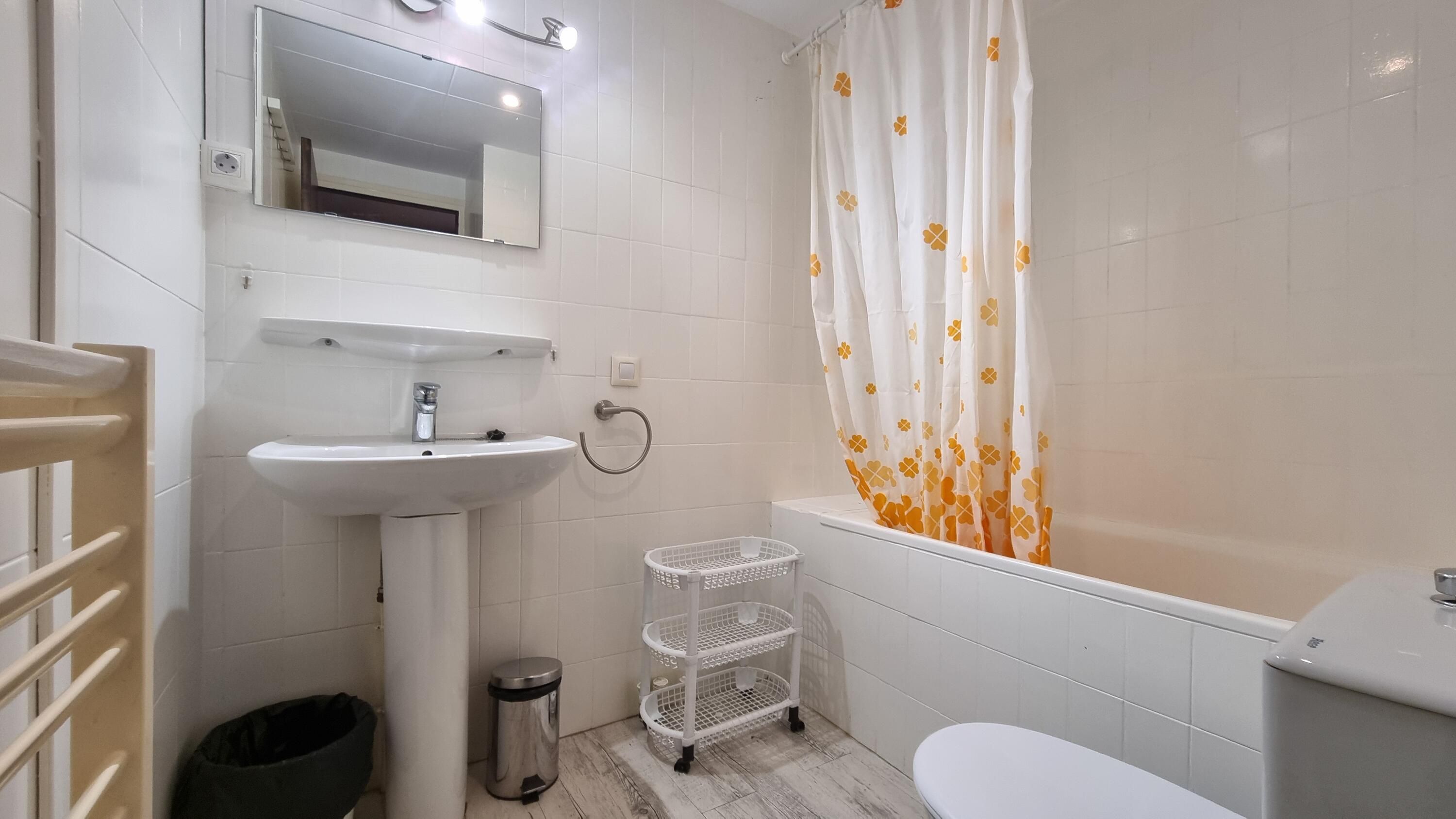 Une salle de bain avec un lavabo blanc, un miroir et des toilettes.