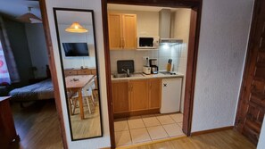 A compact kitchen with wooden cabinets, a microwave, a sink, and a small refrigerator.