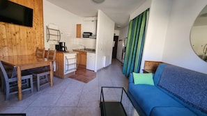 A compact living space with a kitchenette, a dining area, and a seating area with a sofa.