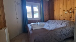 A bedroom with a bed, a wardrobe, a window with curtains, and a star-shaped light fixture.