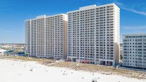 Un hotel de altura con varios balcones, situado junto a la playa.