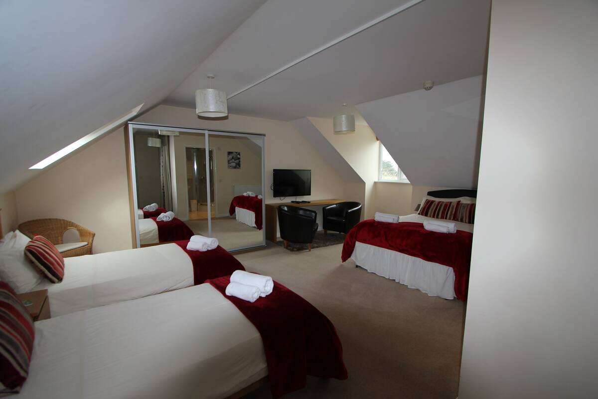Ett hotellrum med två sängar, ett skrivbord, en stol, en TV och en skjutdörr i glas som leder ut till en balkong.