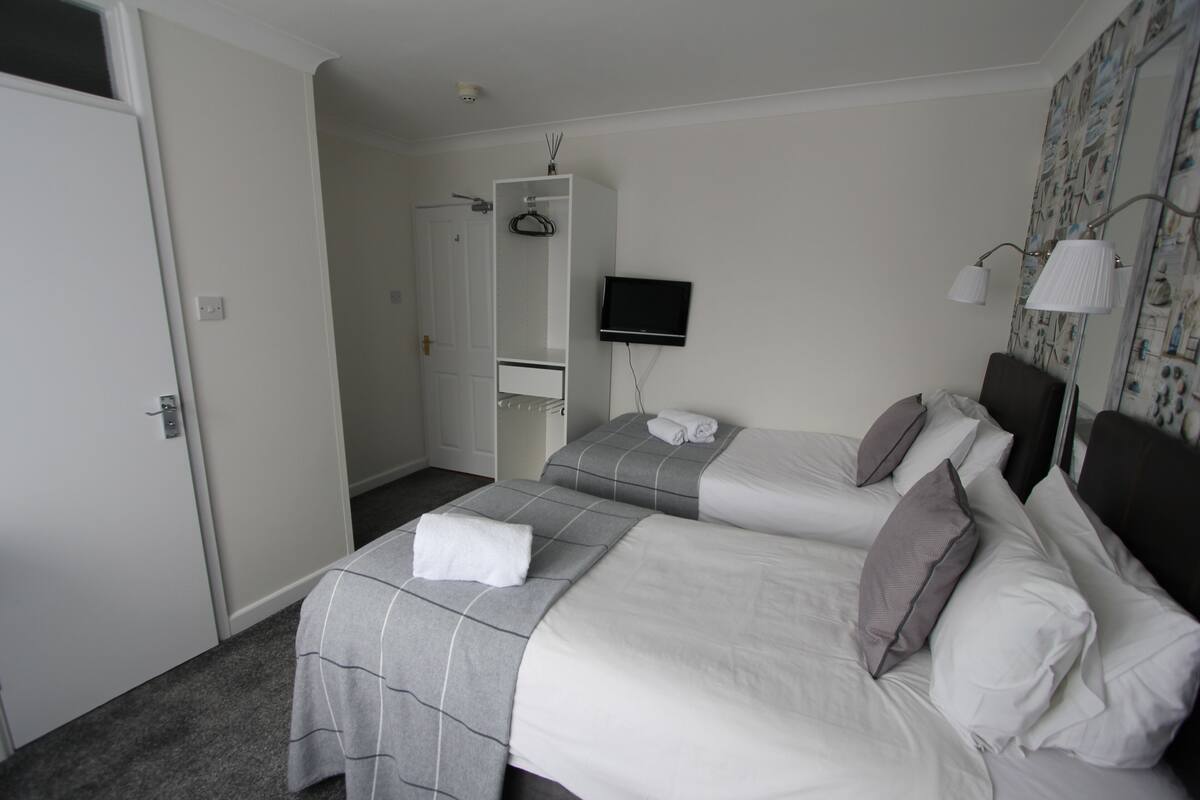 Ett hotellrum med två sängar, en TV, en garderob och en spegel.