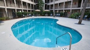 A swimming pool with a metal ladder, surrounded by lounge chairs and umbrellas.