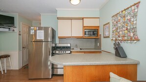 A compact kitchen with a refrigerator, microwave, stove, and a small island counter.