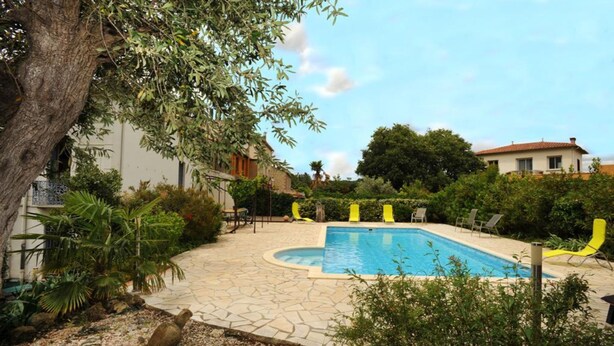 A swimming pool with a stone deck, surrounded by greenery and a tree. - L'escalivade Chambres d'hôtes (Ceret)