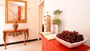 A room with a mirror, a vase with dried plants, a bowl of cherries, and a red dresser. - L'escalivade Chambres d'hôtes (Ceret)