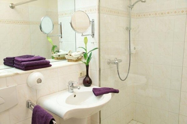 A bathroom with a sink, mirror, towel rack, and shower.