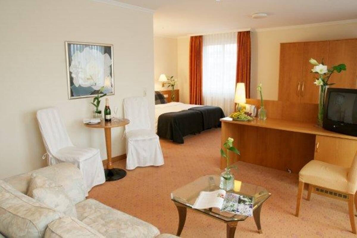 A hotel room with a bed, a desk, a chair, a sofa, and a television.