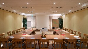 Una sala de conferències amb una taula llarga, cadires, un ordinador portàtil i una pantalla projectora.
