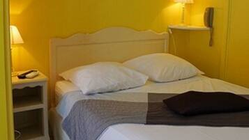 A bed with white bedding, a nightstand with a lamp, and a painting on the wall.