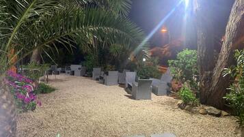 Een terras met stoelen en tafels, omgeven door grind en planten.