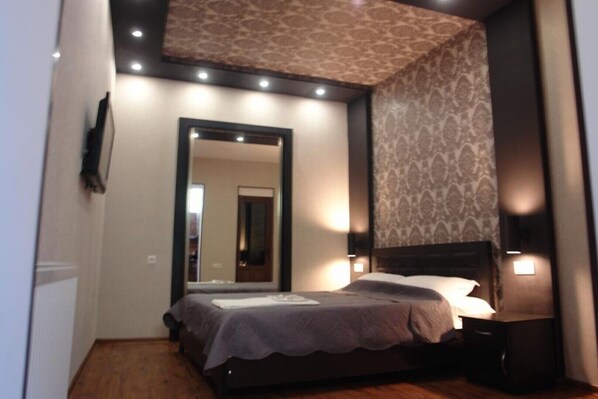 Relax in a stylish room with a large bed, nightstand, and mirror.