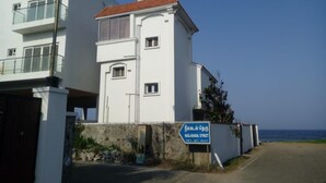 Un edificio de dos pisos con balcón, un letrero que dice 'Neelakadal Street' y vista al mar.