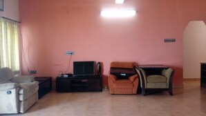 Una sala de estar con pared rosa, ventilador de techo, televisor de pantalla plana, sofá y una pequeña mesa.