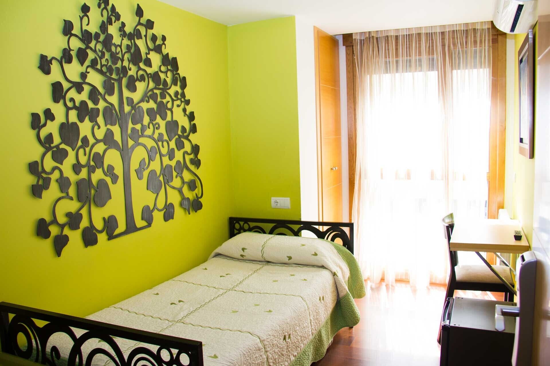 Una habitación con cama, escritorio y una obra de arte en la pared.