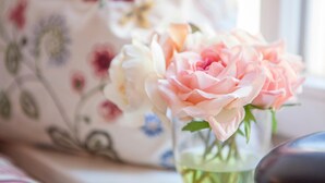 A floral-patterned fabric, possibly a tablecloth or upholstery, with a vase containing pink and white flowers. - Hotel am Markt (Hungen)