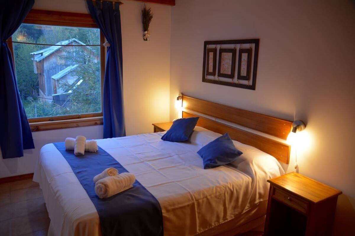 A neatly made bed with blue and white bedding, a wooden headboard, and bedside lamps.