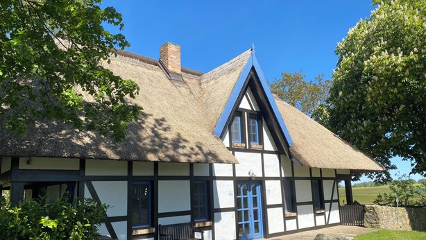 A traditional half-timbered house with a thatched roof, a stone wall, and a bench outside. - Landhaus Szczecin Lagoon, house3 (Dargen)