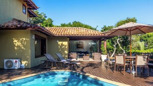 Ein Schwimmbecken mit Liegestühlen und einer überdachten Terrasse.
