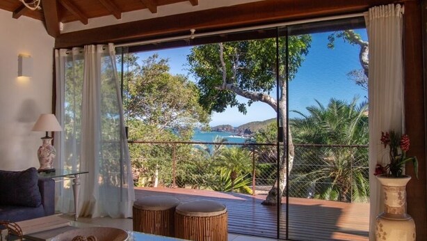 Ein Zimmer mit einer großen Schiebetür, die auf eine Terrasse mit Blick auf das Meer und die Hügel führt.