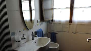 Un bagno con lavandino, specchio e water.