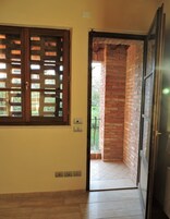 Una stanza con una porta in legno che dà su un balcone con un muro in mattoni.