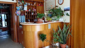 A reception area with a wooden counter, potted plants, and various items on shelves. - Coste Del Lago (Limosano)