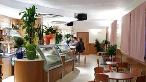 A cafe with wooden furniture, a glass display case, and potted plants. - Coste Del Lago (Limosano)