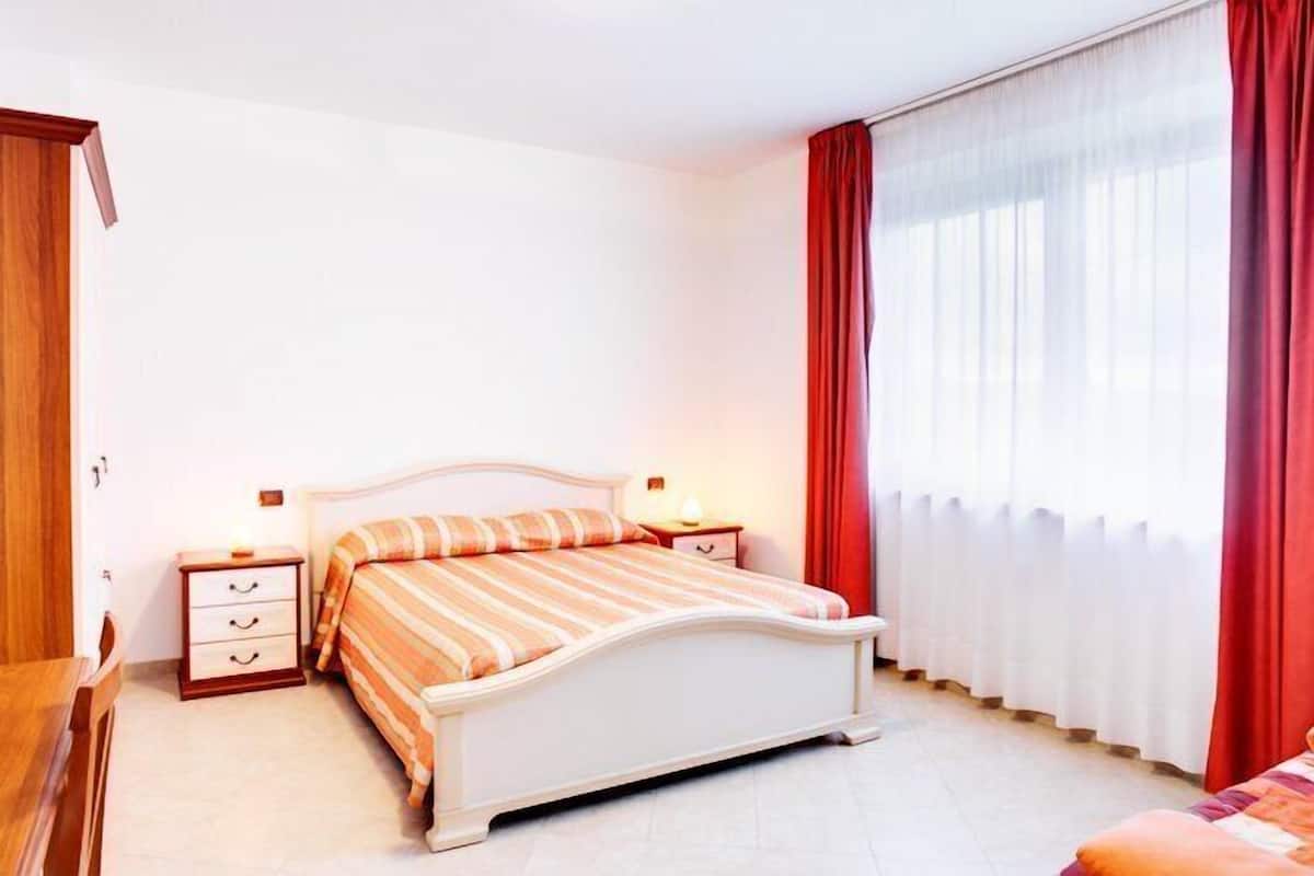 A bedroom with a bed, nightstands, and a window with curtains.
