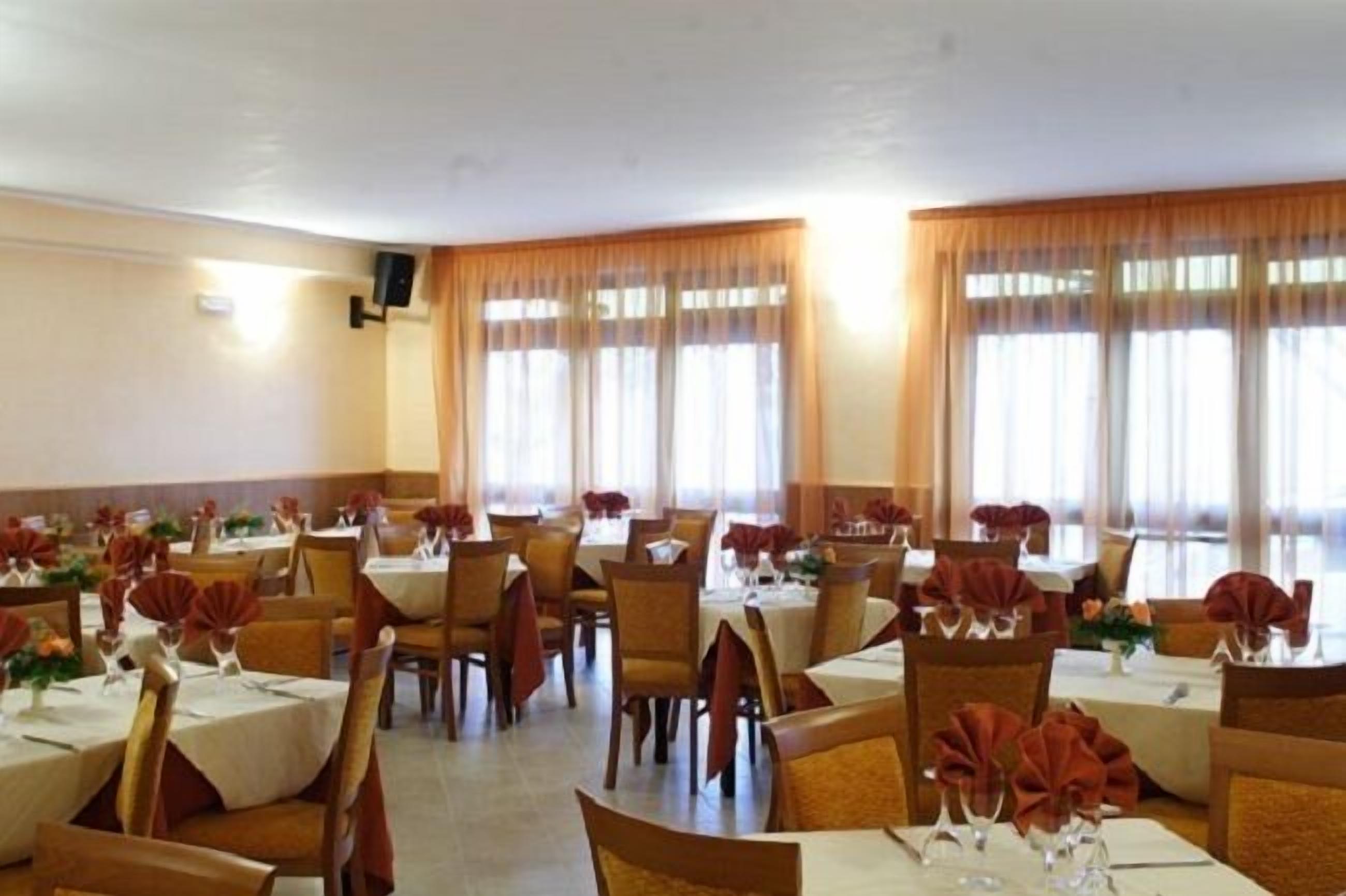 A dining area with multiple tables set for service, featuring a consistent layout and decor.