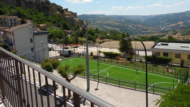 A view of a sports field with a building in the background. - Coste Del Lago (Limosano)