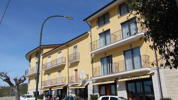 Un hotel amarillo de varios pisos con balcones, restaurante y bar de aperitivos.