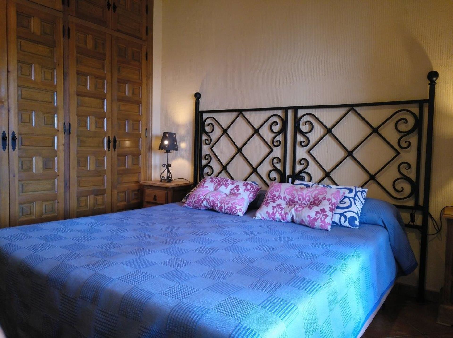 Ein Schlafzimmer mit Bett, Holzschrank und Nachttisch mit Lampe.
