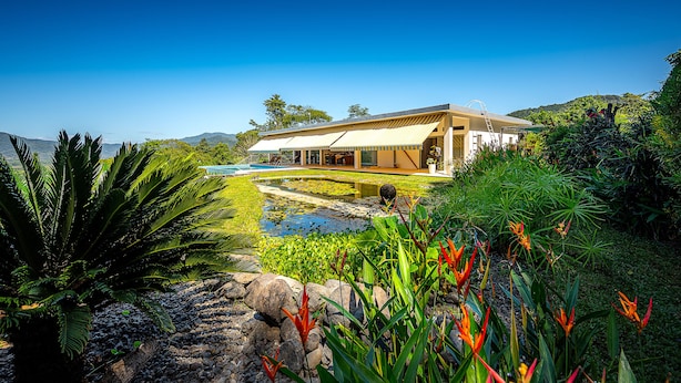 A modern house with a large patio, a swimming pool, and lush greenery. - Casa Laureles (Bejuco)