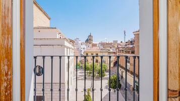 Un balcón con vista a un paisaje urbano, que incluye un edificio destacado con una torre.