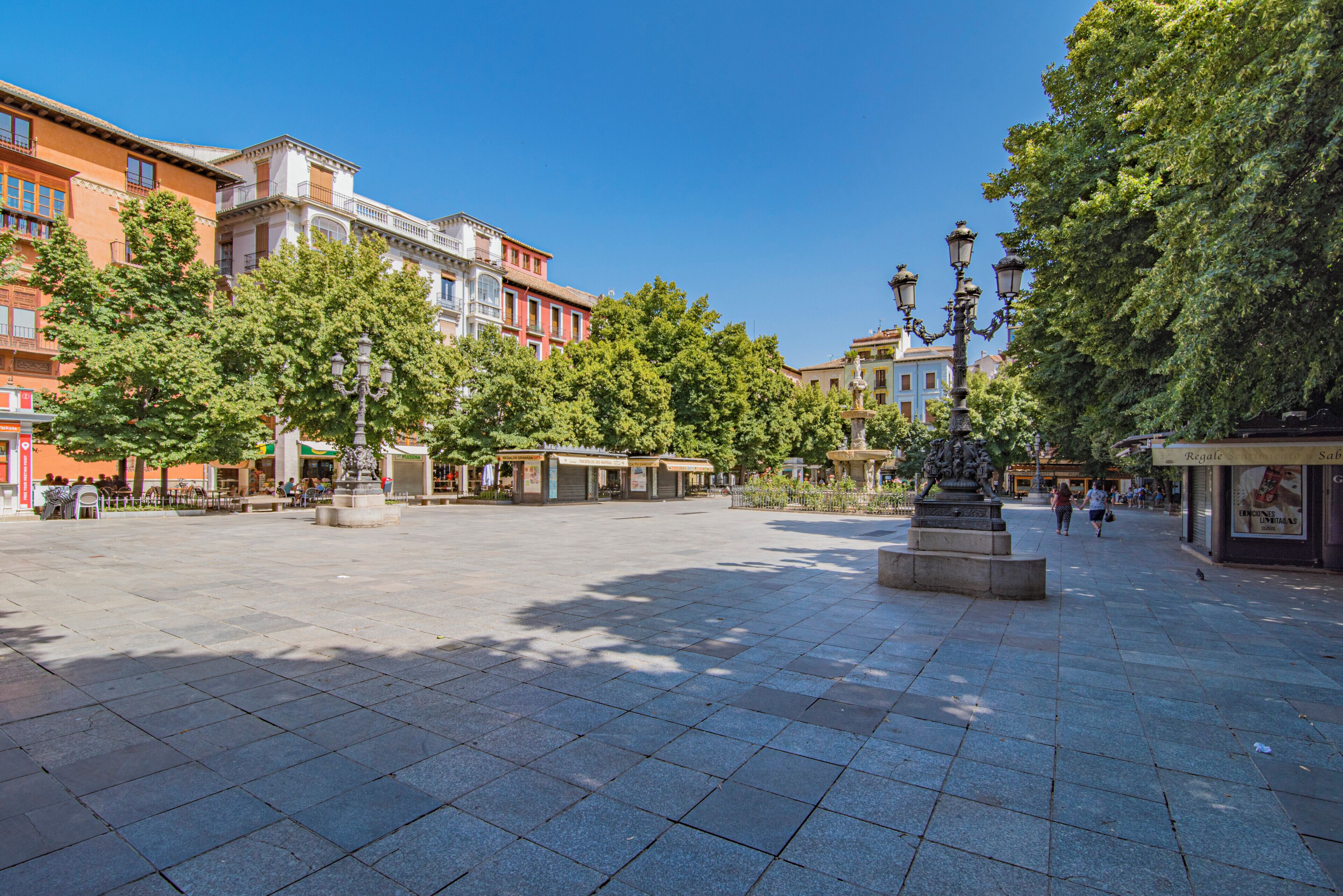 A spacious public square with a fountain, surrounded by trees and historic buildings.